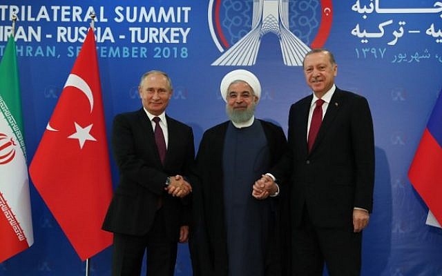 A handout picture taken and released on September 7, 2018 by the Turkish Presidential Press service shows Turkish President Recep Tayyip Erdogan (R) , Iranian President Hassan Rouhani (C) and Russian President Vladimir Putin (L) joining hands  during a trilateral summit in Tehran. (AFP/Turkish Presidency Press Office)