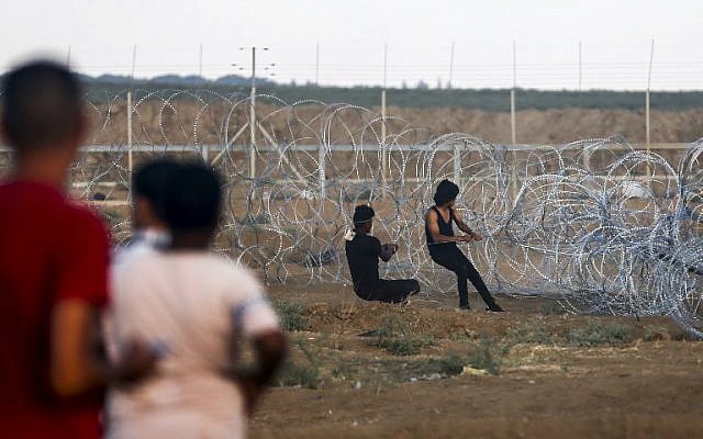 Illustrative. Palestinians pull on a cable tied to a barbed-wire fence as they try to pull down a section of the security fence between the Gaza Strip and Israel, during border clashes east of Gaza City, on September 7, 2018. (AFP/Said Khatib)