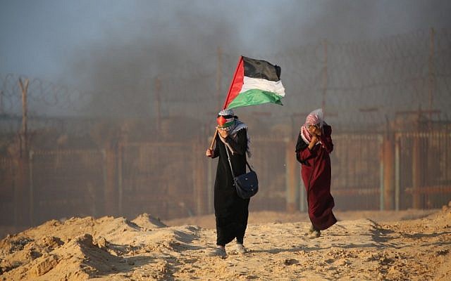 A Palestinian woman carries her national flag during a  protest for lifting the Israeli blockade on Gaza on a beach in Beit Lahia near the maritime border with Israel, on September 17, 2018. (AFP/Said Khatib)