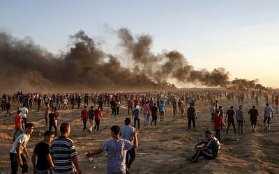 Palestinian protesters gather during a demonstration along the Israeli border fence east of Gaza City on September 21, 2018 as smoke plumes billow from burning tires in the background. (AFP/Said Khatib)