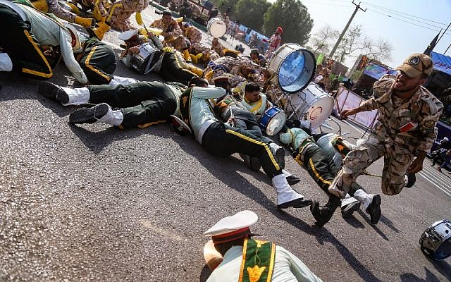 An Iranian soldier runs past injured colleagues lying on the ground at the scene of an attack on a military parade in Ahvaz, September 22, 2018. (AFP/ ISNA / MORTEZA JABERIAN)