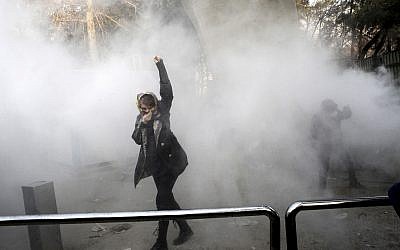 In this Dec. 30, 2017 file photo, taken by an individual not employed by the Associated Press and obtained by the AP outside Iran, a university student attends a protest inside Tehran University while a smoke grenade is thrown by anti-riot Iranian police, in Tehran, Iran (AP Photo, File)