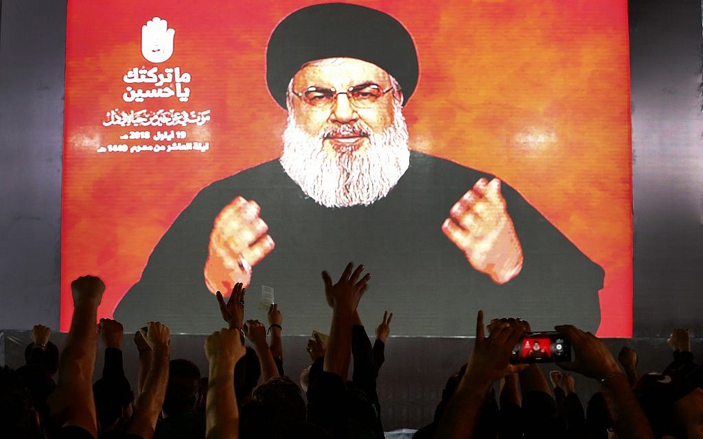 Hezbollah leader Sheik Hassan Nasrallah speaks via a video link, as his supporters raise their hands, during activities to mark the ninth of Ashura, a 10-day ritual commemorating the death of Imam Hussein, in a southern suburb of Beirut, Lebanon, on September 19, 2018. (AP Photo/Hussein Malla)