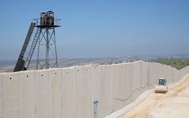 Un véhicule de construction israélien conduit par un mur de béton construit le long de la «Ligne bleue» séparant Israël et le Liban, alors que des membres des Forces armées libanaises regardent depuis une tour de garde près de la ville israélienne de Rosh Hanikra, le 5 septembre 2018. Ari Gross / Times of Israel)