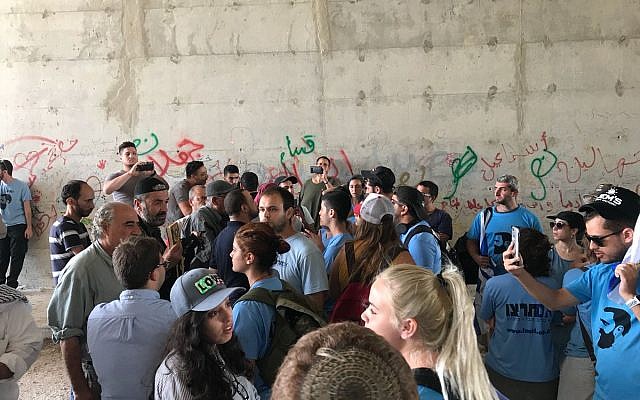 Israeli right-wing activists in blue shirts exchange shouts with Palestinian activists and local residents in a passageway under the Route 1 highway near the West Bank Bedouin village of Khan al-Ahmar, September 7, 2018. (Twitter screen capture)