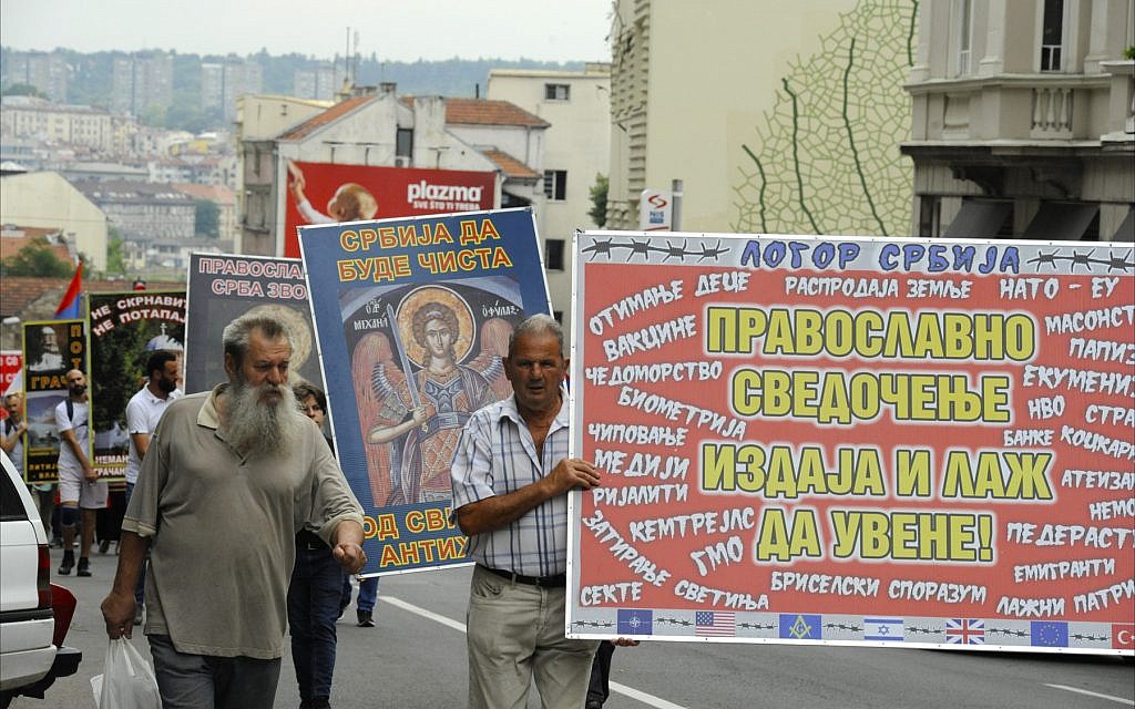 In June 2018, Serb nationalists march along a Belgrade street, carrying banners that protest the desecration of Serbian Orthodox churches and blame the country’s economic problems on 'evil foreign influences' such as NATO, the World Bank, reality TV, the EU, Masons, genetically modified food, Israel and the United States. (Larry Luxner/Times of Israel)