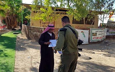 A Civil Administration official hands a notice regarding the pending demolition of Khan al-Ahmar to one of its residents on September 23, 2018. (Civil Administration)