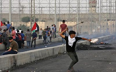 A Palestinian uses a slingshot to hurl a stone during clashes at the Erez border crossing with Israel in the northern Gaza Strip on October 3, 2018. (AFP Photo/Said Khatib)