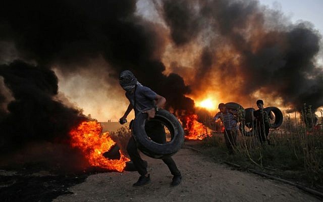 Palestinian protesters carry tires as smoke billows at the Israel-Gaza border, east of Gaza city, on October 12, 2018. (SAID KHATIB / AFP)