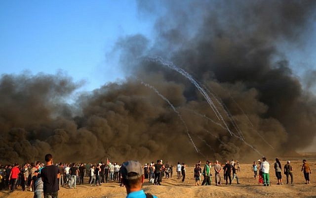 Palestinian protesters gather in the smoke billowing from burning tires as Israeli forces launch tear gas canisters at the Israel-Gaza border, east of Gaza city,  October 12, 2018. (SAID KHATIB/AFP)