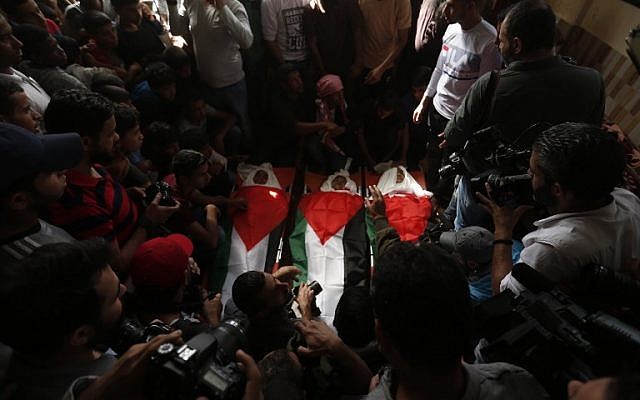 Mourners carry the bodies of three teens, wrapped in Palestinian flags, who were killed in an Israeli airstrike during their funeral in the town of Deir el-Balah, central Gaza Strip, October 29, 2018. (MAHMUD HAMS / AFP)