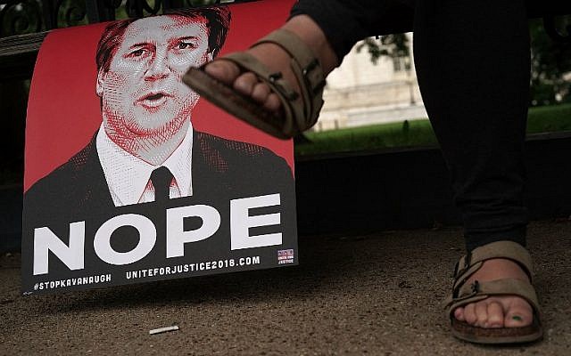 An activist sits next to a 'NOPE' poster of Judge Brett Kavanaugh October 5, 2018 on the ground of the US Capitol in Washington, DC. (Alex Wong/Getty Images/AFP)