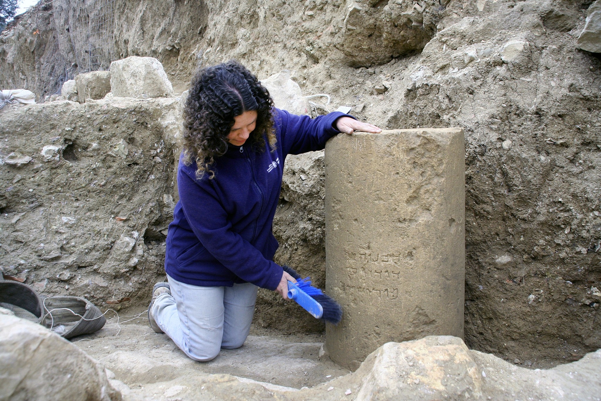 Danit Levi, director of the excavations on behalf of the Israel Antiquities Authority, beside the inscription as found in the field near the Jerusalem International Convention Center, winter 2018. (Yoli Shwartz, IAA)