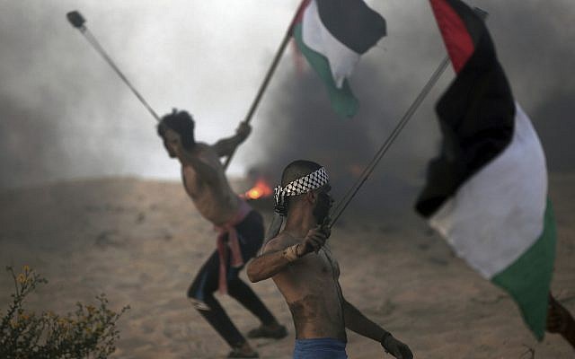 Palestinian protesters hurl stones at Israeli troops during a protest on the beach at the border with Israel near Beit Lahiya, northern Gaza Strip, Oct. 22, 2018. (AP Photo/Khalil Hamra)