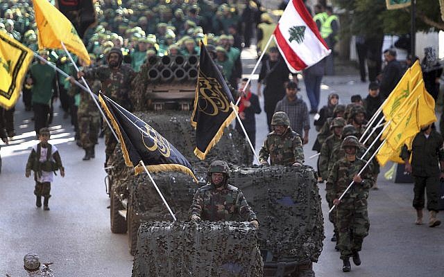 Hezbollah fighters stand on their armed vehicles and hold their party flags, as they parade during a rally to mark the 13th day of Ashoura, in the southern market town of Nabatiyeh, Lebanon, November 7, 2014. (AP Photo/Mohammed Zaatari)