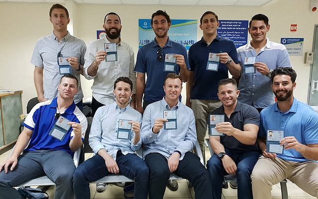Ten American baseball players show off their new national identity cards after receiving Israeli citizenship at the Population and Immigration Authority offices in Jaffa on October 17, 2018. (Israel Baseball via JTA)