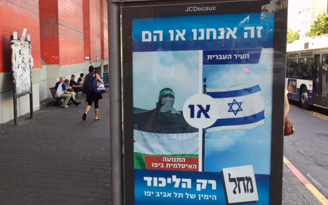 A bus station poster that is part of the "It's Us or Them" campaign mounted by the Likud in Tel Aviv-Jaffa ahead of local elections in October 2018 (ToI staff)