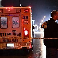 An FBI agent stands behind a police cordon and an ambulance outside the Tree of Life Synagogue (L) after a shooting there left 11 people dead in the Squirrel Hill neighborhood of Pittsburgh on October 27, 2018. (Brendan Smialowski / AFP)