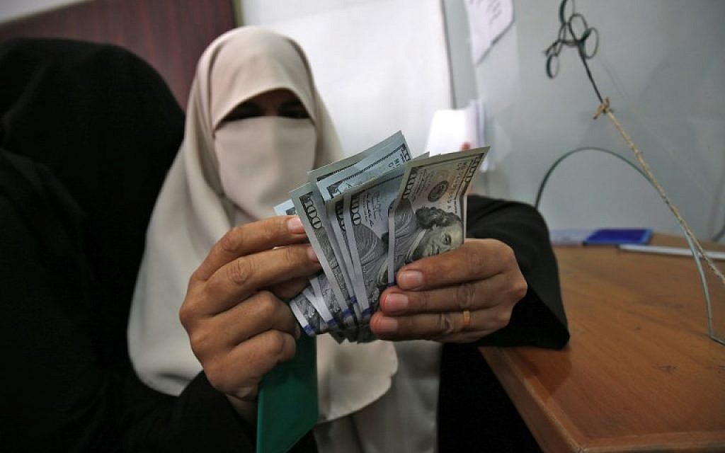 A Palestinian woman counts her money after receiving her salary in Rafah in the southern Gaza Strip, November 9, 2018. (Said Khatib/AFP)