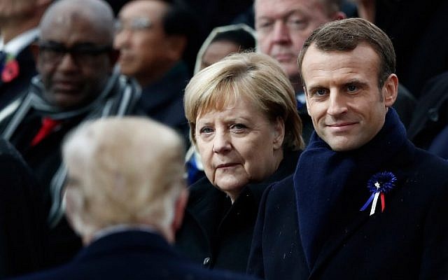 German Chancellor Angela Merkel (C) and French President Emmanuel Macron (R) react as US President Donald Trump (front L) arrives to attend a ceremony at the Arc de Triomphe in Paris on November 11, 2018 as part of commemorations marking the 100th anniversary of the 11 November 1918 armistice, ending World War I. (BENOIT TESSIER / POOL / AFP)