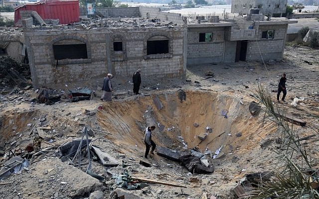Palestinians inspect a crater caused by an Israeli airstrike earlier this week during fighting with Palestinian terror groups, in Rafah in the southern Gaza Strip, on November 14, 2018. (Said Khatib/AFP)
