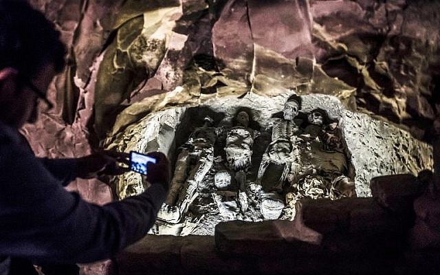 This picture taken on November 24, 2018 shows a man using a cell phone to take a picture of a group of mummies stacked together at the site of Tomb TT28, which was discovered by an Egyptian archaelogical mission at Al-Assasif necropolis on the west bank of the Nile north of the southern Egyptian city of Luxor. (Khaled DESOUKI / AFP)
