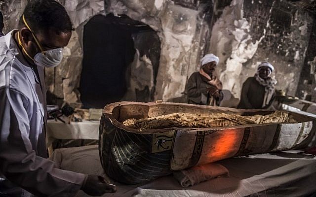 This picture taken on November 24, 2018 shows Egyptian workers and archaeologists standing next to an opened intact sarcophagus containing a well-preserved mummy of a woman named "Thuya" wrapped in linen, discovered by a French mission at the site of Tomb TT33 which dates to the 18th dynasty (16th-13th century BC) at Al-Assasif necropolis on the west bank of the Nile north of the southern Egyptian city of Luxor. (Khaled DESOUKI / AFP)