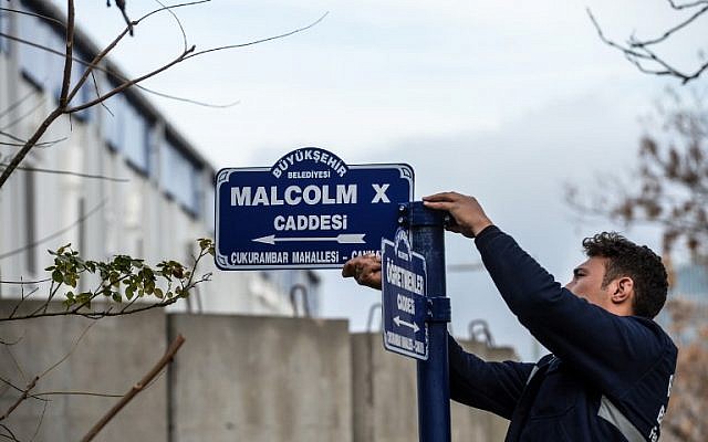 An Ankara metropolitan municipality worker hangs the road sign for 'Malcolm X Avenue,' named after the human rights activist, where the new US Embassy is being built, in Ankara, on November 29, 2018. (AFP)