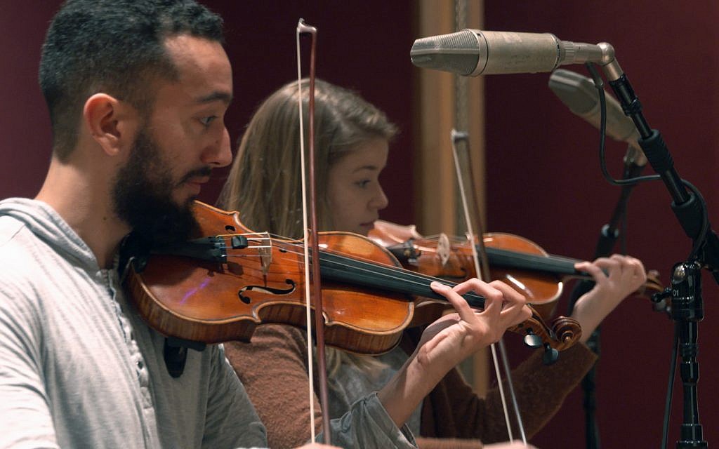 In this Nov. 7, 2018, photo provided by the University of Michigan, student violinists Reuben Kebede and Dana Johnson perform at a recording session in Ann Arbor, Michigan, with Contemporary Directions Ensemble recording "The Most Beautiful Time of Life," as it's translated from German to English (Christopher Boyes/University of Michigan via AP)