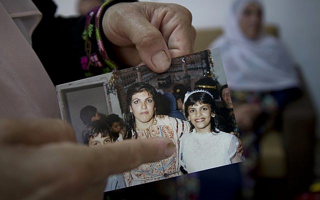 In this August 8, 2018, photo, Fadwa Tlaib, an aunt of Rashida Tlaib, points to a young Rashida in a 1987 picture with her mother Fatima and brother Nader, at the family house in the West Bank village of Beit Ur al-Foqa. (AP/Nasser Nasser)