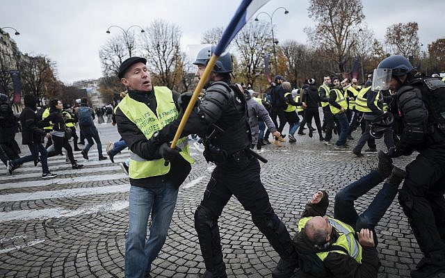 Protestors wearing yellow jackets clash with riot police officers on the Champs-Elysees avenue in Paris, Nov.24, 2018 (AP Photo/Kamil Zihnioglu)