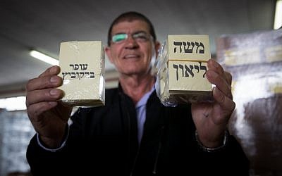 A man holds voting notes of Jerusalem mayoral candidates Ofer Berkovich and Moshe Lion, during preparations for the upcoming second round of the Jerusalem municipal elections, at a warehouse in Jerusalem on November 11, 2018. (Yonatan Sindel/Flash90)