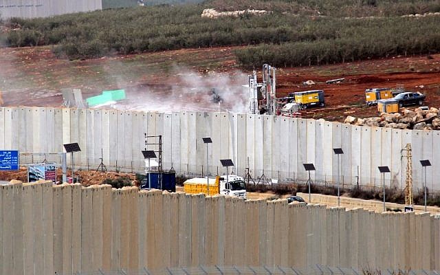 This picture taken on December 4, 2018, from the southern Lebanese village of Kfar Kila shows a view of Israeli machinery operating behind the border wall in Israel (R). (Ali DIA / AFP)