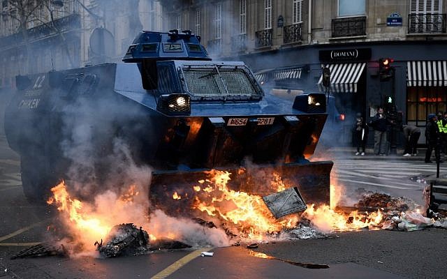 A gendarmerie armored vehicle drives past fires lit during "yellow vest" protests near the Champs Elysees avenue in Paris on December 8, 2018. (Bertrand Guay/AFP)