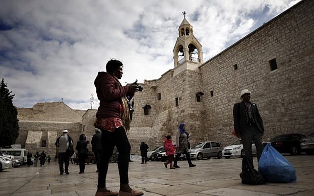 Tourists and Christian pilgrims take pictures outside of the Church of the Nativity, revered as the site of Jesus's birth, in the West Bank city of Bethlehem, on December 12, 2018. (Thomas Coex/AFP)