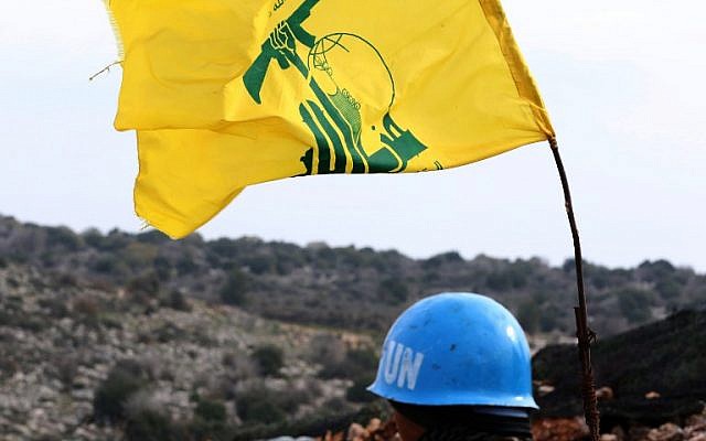A picture taken from the southern Lebanese village of Meiss al-Jabal on December 16, 2018, shows a United Nations Interim Forces in Lebanon (UNIFIL) soldier monitoring the border between Lebanon and Israel. On his right is a flag of the Lebanese Shiite terror group Hezbollah. (Mahmoud Zayyat/AFP)