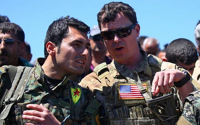 A file photo taken on April 25, 2017, shows a US military officer (R) speaking with a fighter from the Kurdish People's Protection Units (YPG) at the site of Turkish airstrikes near the northeastern Syrian Kurdish town of Derik, known as al-Malikiyah in Arabic. (Delil Souleiman/AFP)