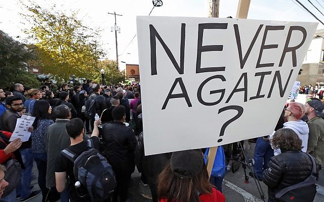 A person holds a sign during a protest gathering on the block of the Jewish Community Center in the Squirrel Hill neighborhood of Pittsburgh, where the funeral for Dr. Jerry Rabinowitz, Tuesday Oct. 30, 2018. (AP/Gene J. Puskar)