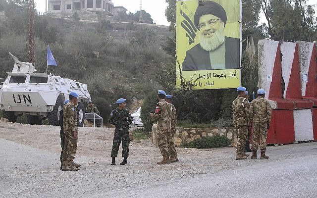 Indonesian UN peacekeepers stand in front a poster of Hezbollah leader Sheikh Hassan Nasrallah, as they patrol the Lebanese side of the Lebanese-Israeli border in the southern village of Kfar Kila, Lebanon, Tuesday, December 4, 2018. (AP/Mohammed Zaatari)
