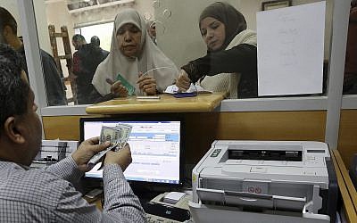 A Hamas-appointed government employee in Gaza signs a document to receive 50 percent of her long-overdue salary from funds donated by Qatar, while others wait in the queue, at the main Gaza Post Office, in Gaza City, December 7, 2018. (AP Photo/Adel Hana)