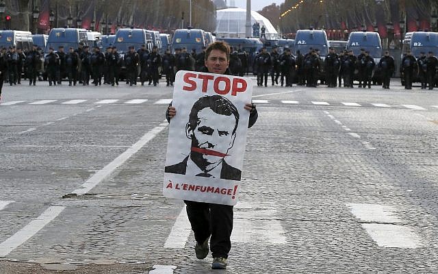 A demonstrator holds a portrait of France's President Emmanuel Macron during a protest on Paris' famed Champs-Elysees Avenue, France, Dec. 8, 2018 (AP Photo/Michel Euler)