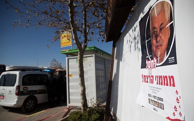 A poster showing Palestinian President Mahmoud Abbas with a text reading 'Assassinate murder funders' hanging on a bus station at the entrance to the Israeli settlement of Geva Binyamin, in the West Bank on December 11, 2018. (Yonatan Sindel/Flash90)