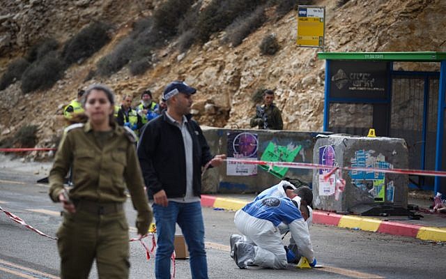 Israeli soldiers, medical officials and police inspect the scene of a terrorist shooting attack near Givat Assaf, in the central West Bank, on December 13, 2018. (Hadas Parush/Flash90)