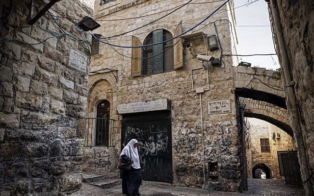 A Palestinian woman walks past a house in the Muslim Quarter of the Old City of Jerusalem which was bought by Jewish Israelis, on December 4, 2019. (THOMAS COEX/AFP)