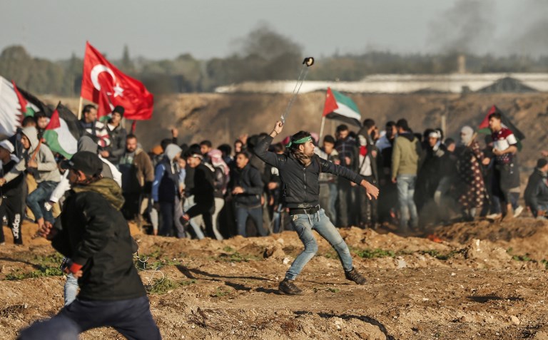 Illustrative: A Palestinian protester uses a slingshot to hurl stones at Israeli forces across the border fence, during clashes following a demonstration along the border with Israel east of Gaza City on January 11, 2019. (Mahmud Hams/AFP)