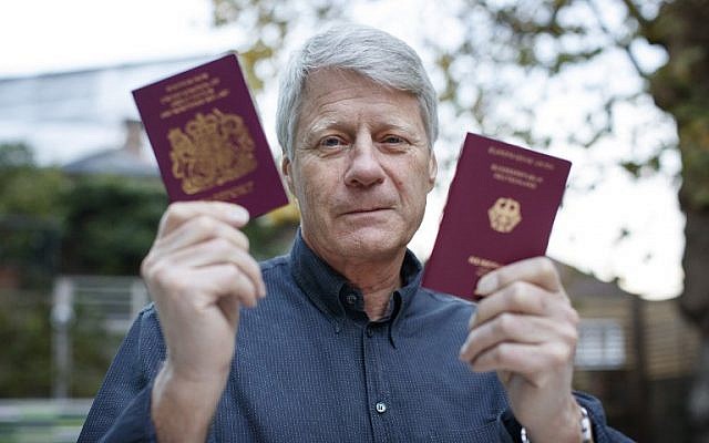 Illustrative: TV presenter Nick Ross poses with his British (L) and German passports at his home in London on November 5, 2018. (TOLGA AKMEN / AFP)