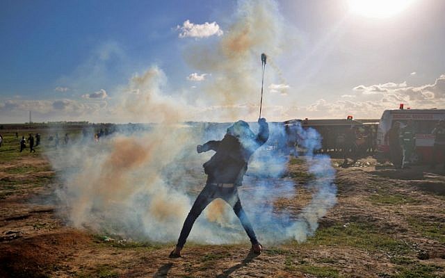 A Palestinian protester uses a slingshot to throw tear gas toward Israeli forces during a demonstration along the Israeli fence east of Gaza City on January 18, 2019. (SAID KHATIB / AFP)