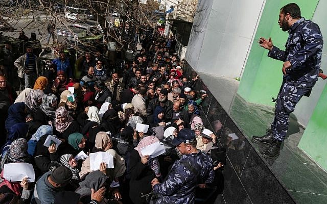 Security forces loyal to Hamas organize a line outside the central post office in Gaza City, on January 26, 2019, as Palestinians gather to receive financial aid from Qatar. (Mahmud Hams/AFP)