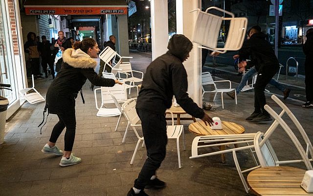 Ethiopian-Israeli protesters trash a sidewalk cafe on Ibn Gabriol Boulevard in Tel Aviv, January 30, 2019. (Luke Tress/Times of Israel)