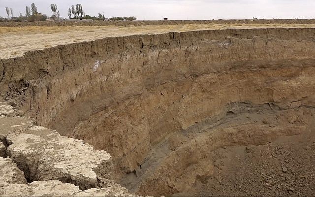 This frame grab from video taken on Aug. 8, 2018, provided by Iranian Students' News Agency, ISNA, shows the edge of a massive hole caused by drought and excessive water pumping in Kabudarahang, in Hamadan province, western Iran. (ISNA via AP)